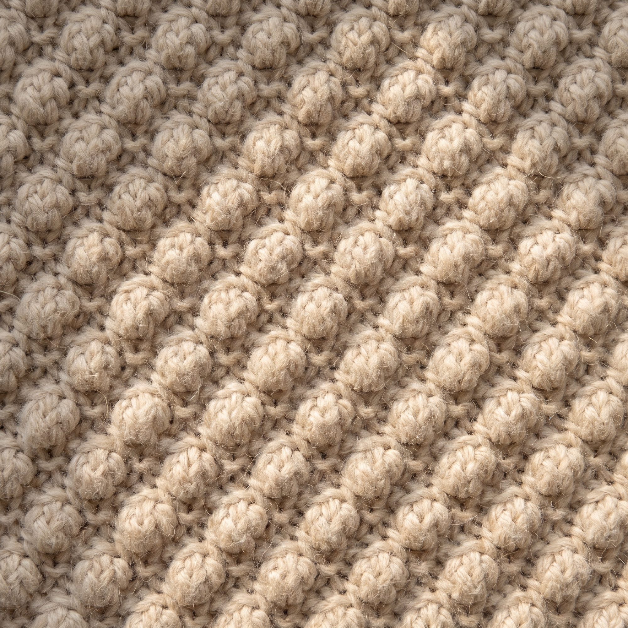 Close macro of ecru popcorn knit, the raised bobble structure lit from the side