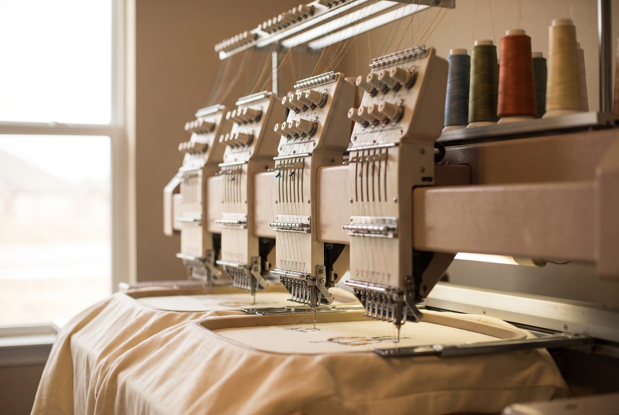 Multi-head embroidery machine running on a stretched fabric panel
