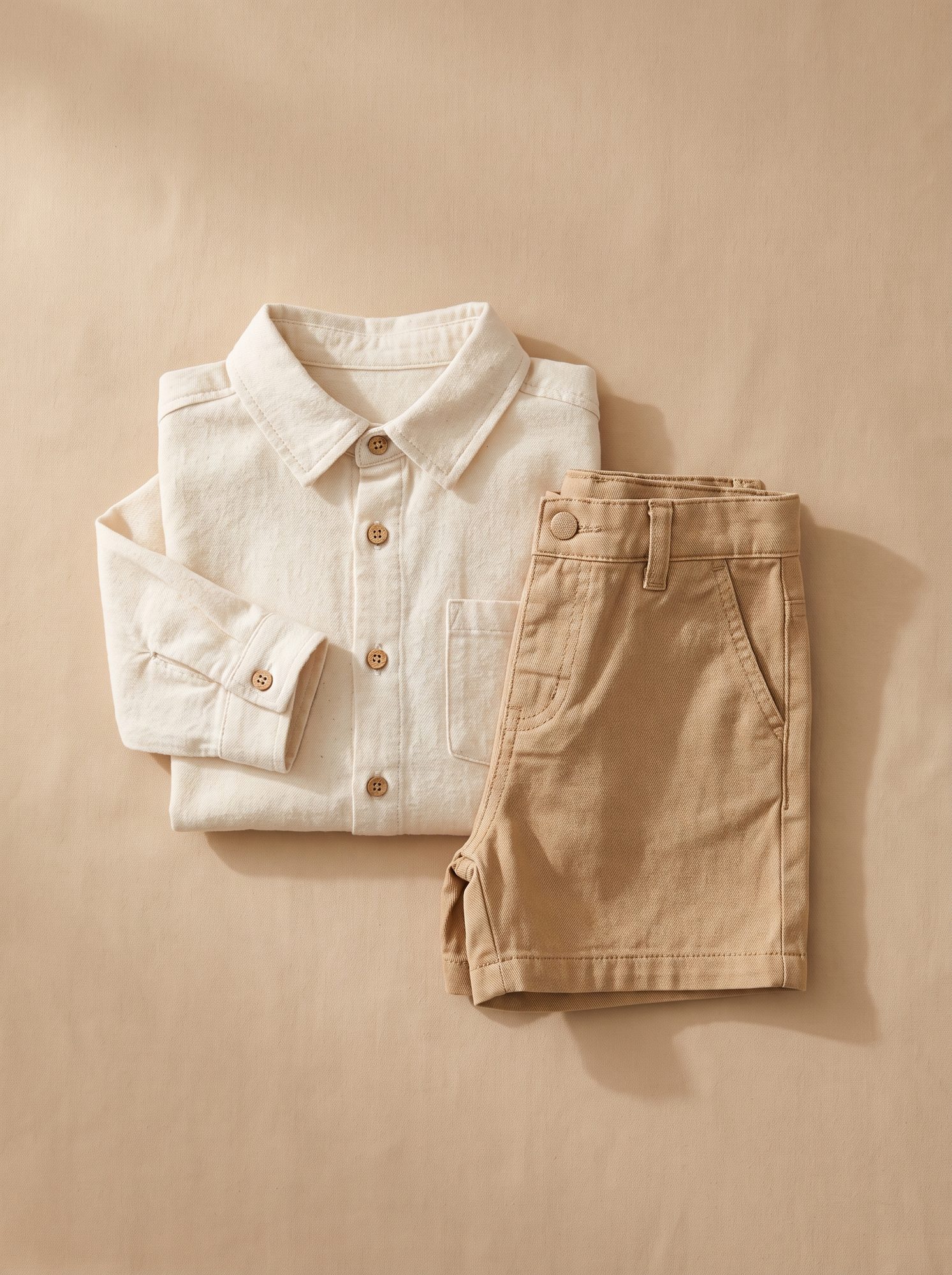 Kids cream corduroy shirt laid flat beside a matching pair of shorts