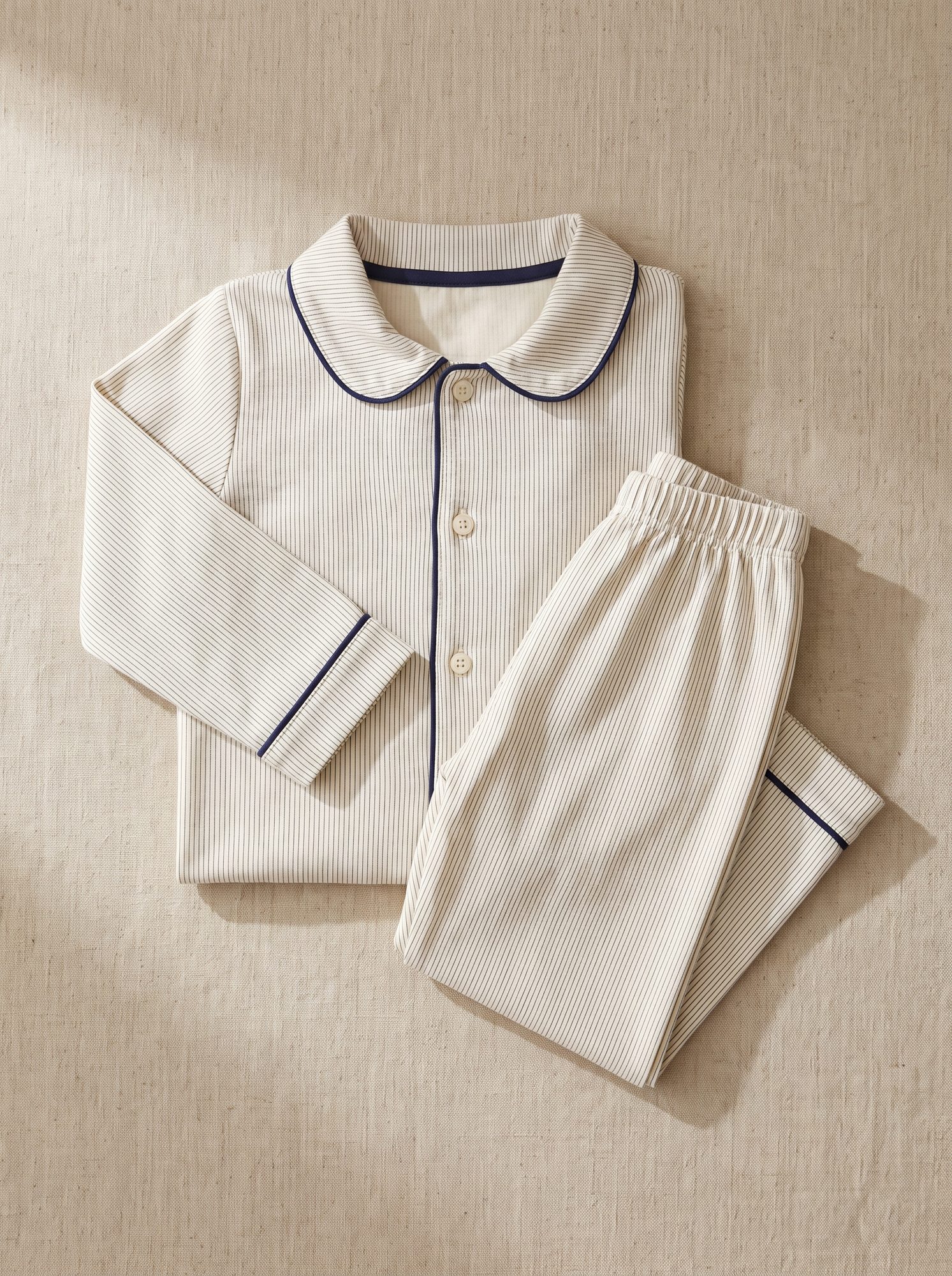 Kids white piped pyjama set with a peter pan collar, laid flat